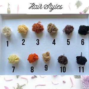 May include: A display of eleven small, textured yarn samples in various colors, arranged in two rows. The samples are numbered and labeled "Hair Styles" in cursive script. Colors include blonde, brown, orange, and black.