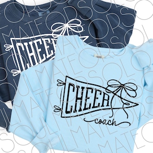 May include: Two long-sleeved sweatshirts, one navy blue and one light blue. Each features a black graphic of a pennant with the word "CHEER" inside, a bow, and the word "coach" in script. The sweatshirts are likely for cheerleading.