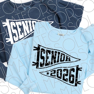 May include: Two sweatshirts, one navy blue and one light blue, each with a white or black pennant design. The pennants read "SENIOR" and "2026", indicating a graduation theme. The sweatshirts are likely for the graduating class of 2026.