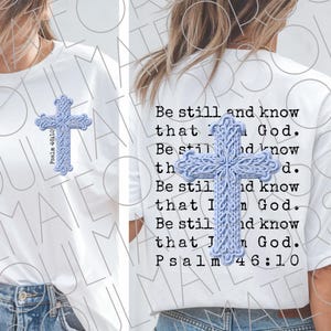 Puede incluir: Camiseta blanca con un diseño de cruz azul claro en la parte delantera y trasera. La cruz delantera tiene el texto "Salmo 46:10" y la trasera tiene el texto "Estad quietos, y conoced que yo soy Dios. Salmo 46:10".