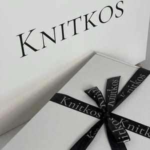 May include: A white gift box with a black ribbon tied in a bow. The ribbon has the word "Knitkos" printed on it in a gray font.