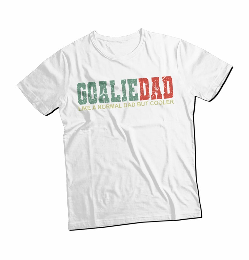 K&ouml;nnte beinhalten: Wei&szlig;es T-Shirt mit einem gr&uuml;n-rot-wei&szlig;en, abgenutzten Aufdruck mit der Aufschrift "Goalie Dad Like a Normal Dad But Cooler".
