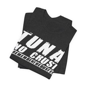 Pu&ograve; includere: Una t-shirt grigio antracite scuro con scritte bianche dall'effetto usurato che recitano TUNA NO CRUST REMEMBER THE BUSTER. La maglietta &egrave; piegata e presenta un girocollo e maniche corte, realizzate in un tessuto dall'aspetto testurizzato.