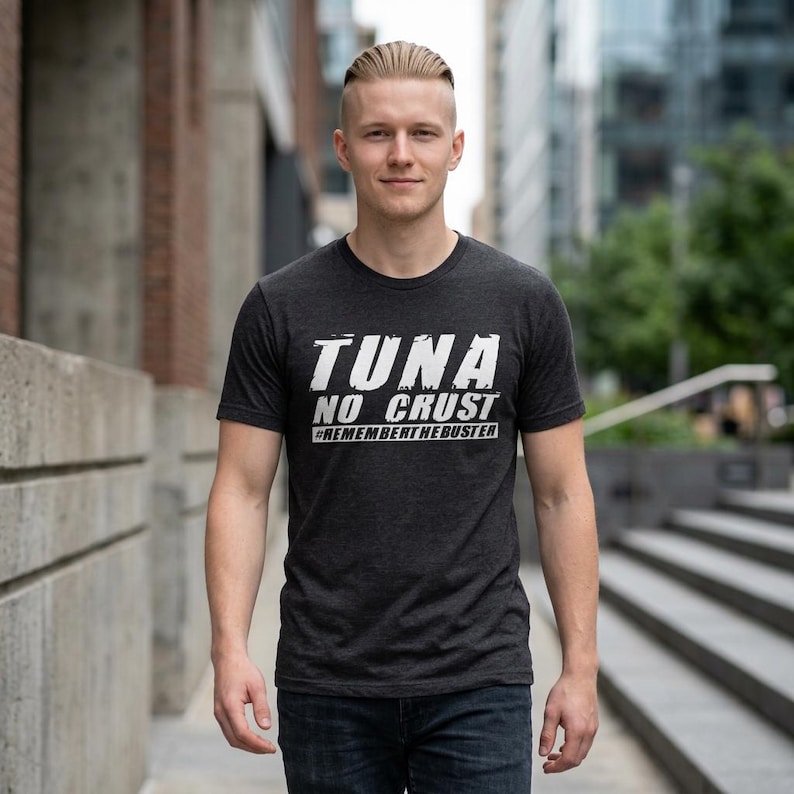 Pu&ograve; includere: Una t-shirt a maniche corte grigio antracite con testo bianco in stile vintage sul petto che recita TUNA NO CRUST e #REMEMBERTHEBUSTER. La maglietta presenta un girocollo e una vestibilit&agrave; standard, realizzata in tessuto m&eacute;lange.
