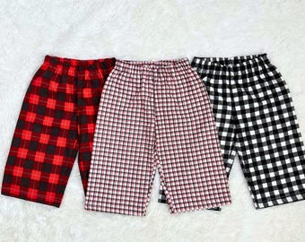 May include: Three pairs of plaid shorts in red and black, red and white, and black and white. The shorts have an elastic waistband and a relaxed fit, perfect for casual wear. The fabric appears to be a soft, lightweight material.