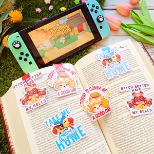 Puede incluir: Un conjunto de diez marcadores de colores con personajes de Animal Crossing. Cada marcador tiene un diseño diferente e incluye texto como "Take Me Home", "Today is Gonna Be a Good Day" y "B*tch Better Have My Bells".