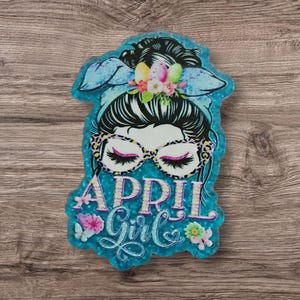 May include: A white ceramic mug with a black handle and the text "But First, Coffee" in a black, handwritten-style font. The mug is on a white surface.