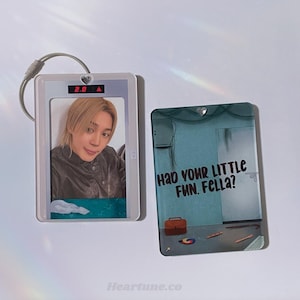 May include: Two clear acrylic keychains. One features a photo of a person, set in a white frame with a silver keychain. The other has a blue background with the text "HAD YOUR LITTLE FUN. FELLA?" and a small briefcase.