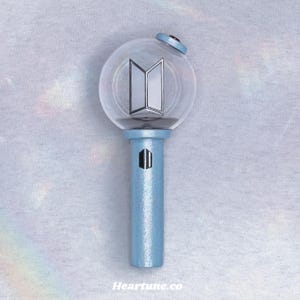 May include: A light blue light stick with a clear, spherical head featuring a silver and white emblem. The handle is light blue with a black rectangular design. The top has a small red accent. The text "Heartune.co" is at the bottom.