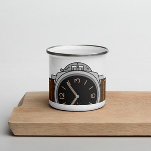 Puede incluir: Taza de esmalte blanco con una ilustración de esfera de reloj en blanco y negro. La esfera del reloj tiene números y manecillas marrones. El reloj tiene una banda plateada y las palabras "REG. T.M." impresas en la parte superior.