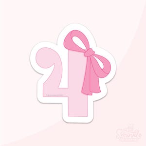 以下が含まれることがあります： ピンク色の数字の4のクッキーカッター。ピンクのリボンが飾られています。クッキーカッターは白い縁取りがあり、下部には「THE SPRINKLE FACTORY」の文字が印刷されています。背景は薄いピンク色です。