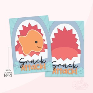 Op de afbeelding: Twee rechthoekige kaarten met een haaienthema. Eén kaart toont een oranje goudvis met een lachend gezicht in een rode, getande bek. De tekst "Snack Attack!" is in zwart script geschreven. De andere kaart toont de open mond.
