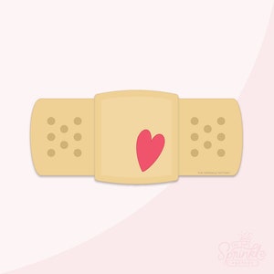 May include: A beige bandage with a pink heart in the center. The bandage has a textured surface with small circles. The text "THE SPRINKLE FACTORY" is printed on the bottom right corner of the bandage.