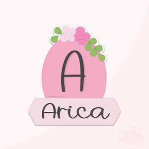 May include: A pink, oval-shaped design with a black letter "A" and a floral arrangement on top. Below, a light pink banner displays the name "Arica" in a cursive font. The design is set against a light pink background.