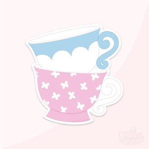 May include: Two teacups stacked on top of each other. The top cup is light blue with a white rim and a white cloud design. The bottom cup is pink with a white floral pattern.