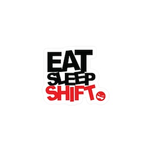 May include: A die-cut sticker featuring the text EAT SLEEP SHIFT in a bold, blocky font. The words EAT and SLEEP are printed in black, while the word SHIFT is in red. A small red circular icon with a stylized face is positioned to the right.