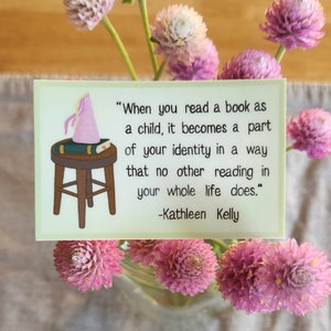 May include: A rectangular card with a light green border features a quote by Kathleen Kelly: "When you read a book as a child, it becomes a part of your identity..." A cartoon illustration of a stool, book, and party hat is on the left.