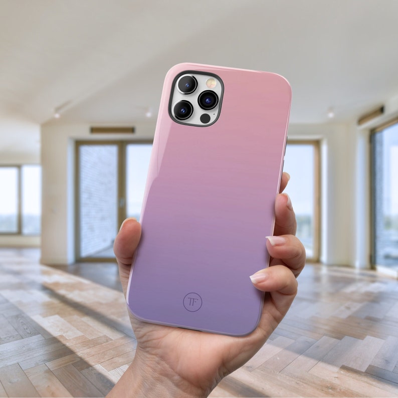 May include: A pink and purple gradient phone case with a clear circle on the back that says "TF".