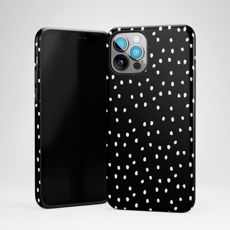 May include: Black phone case with a white polka dot pattern. The case has a cutout for the camera lens.