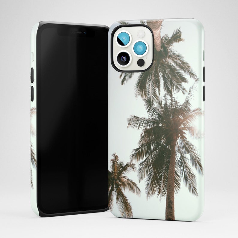 May include: A white phone case with a tropical palm tree design. The case has a cutout for the camera lens and a black border.