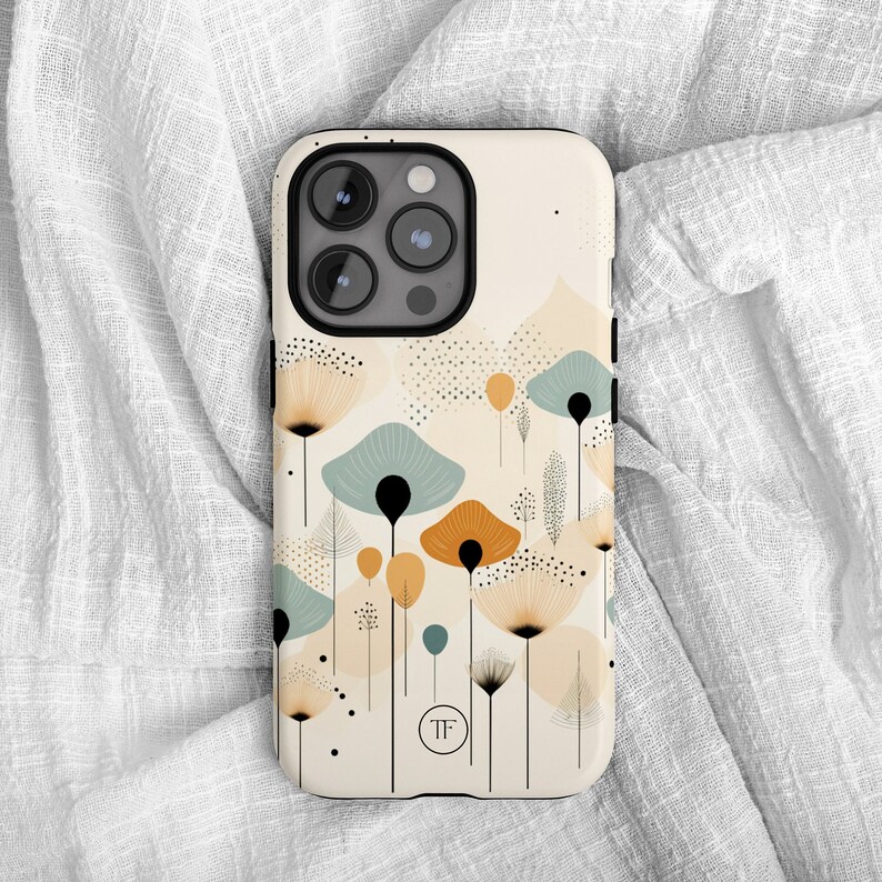 K&ouml;nnte beinhalten: Eine wei&szlig;e Handyh&uuml;lle mit einem schwarzen Kameraobjektiv und einem Design aus abstrakten Blumen in Blaut&ouml;nen, Gelb und Orange. Die H&uuml;lle hat ein kleines Logo mit der Aufschrift "TF".