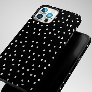 May include: Black phone case with a white polka dot pattern. The case has a raised camera bump with three lenses.
