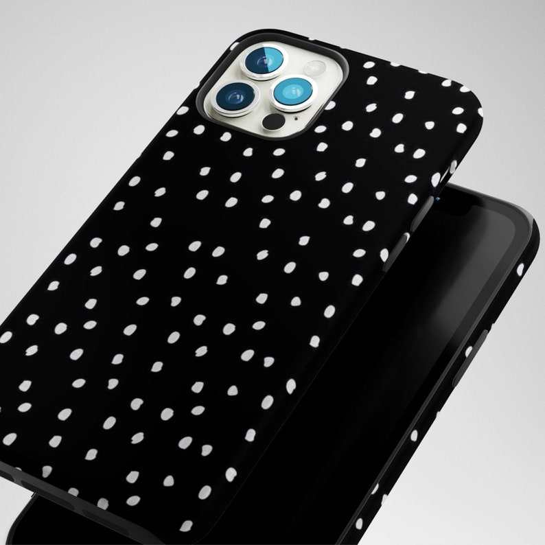 May include: Black phone case with a white polka dot pattern. The case has a raised camera bump with three lenses.