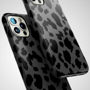 May include: Two black and gray leopard print phone cases. The cases have a glossy finish and a dark gray background. The leopard spots are a darker shade of gray. The phone cases have multiple camera lenses.