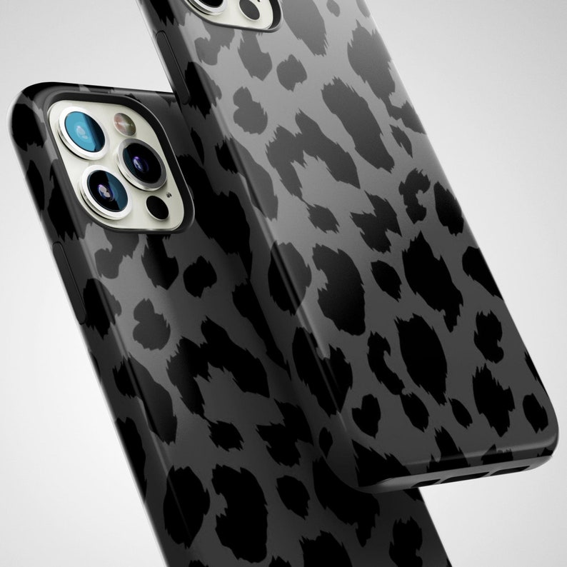 May include: Two black and gray leopard print phone cases. The cases have a glossy finish and a dark gray background. The leopard spots are a darker shade of gray. The phone cases have multiple camera lenses.