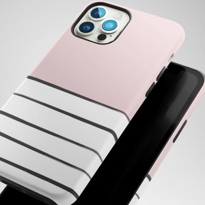 May include: A pink and white striped phone case with a black camera lens cutout. The case is designed for an iPhone with a triple camera lens.
