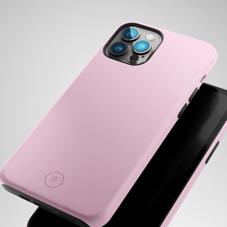 May include: A light pink phone case with a black camera lens and a small circle logo that says "TF".