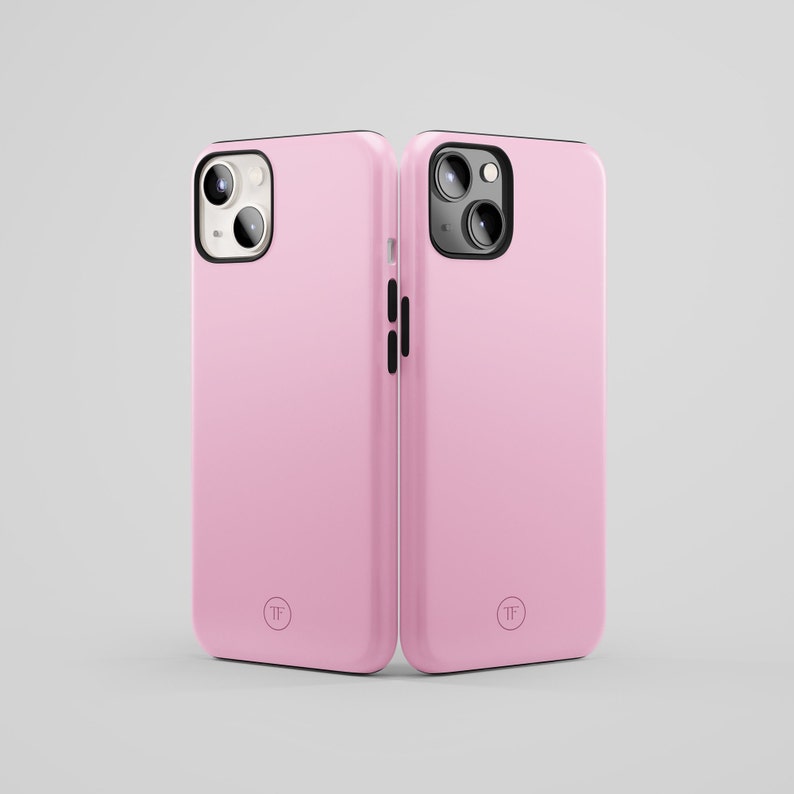 May include: Two pink phone cases with black trim and a camera lens cutout. The cases have a small circle with the letters "TF" in the center.