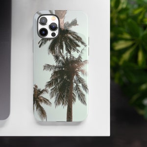 May include: A phone case with a tropical design featuring palm trees against a light blue background.