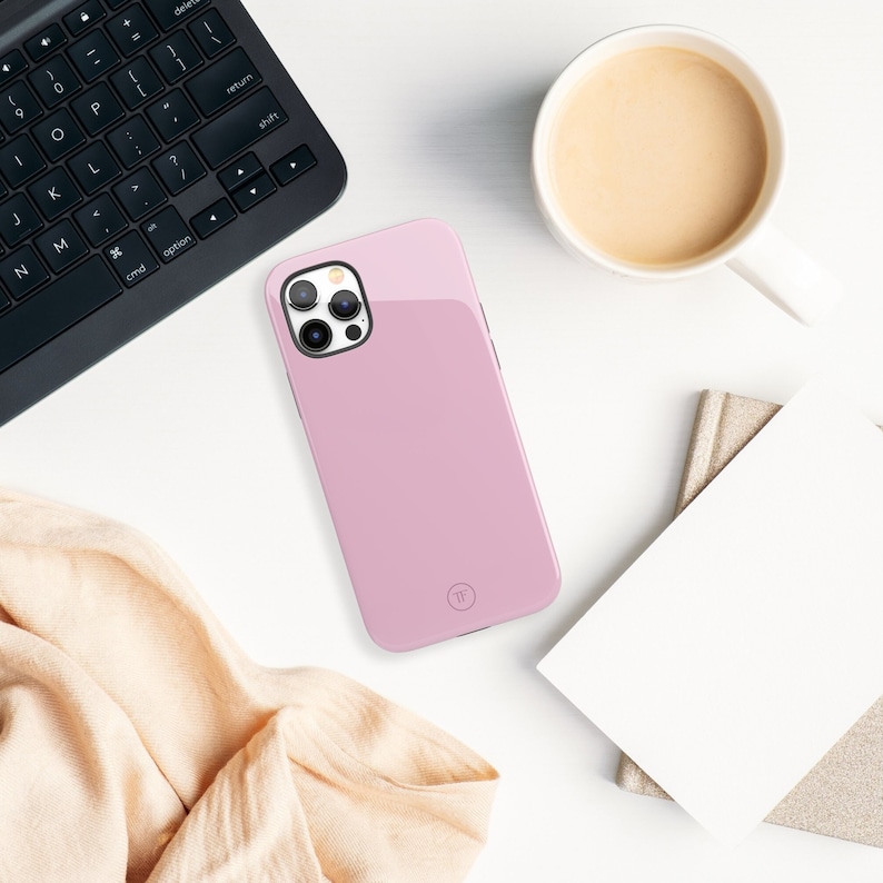 May include: A pink phone case with a clear camera lens cover and a small circle logo on the back.