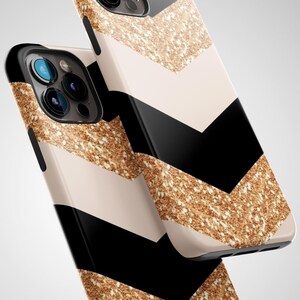 Puede incluir: Una funda para tel&eacute;fono negra y dorada con un patr&oacute;n de chevron. La funda est&aacute; hecha de un material pl&aacute;stico duro y tiene un acabado brillante.