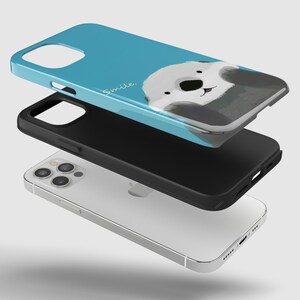 May include: A blue phone case with a cartoon otter on it. The otter is smiling and the case says "Smile." The case is shown in three parts, with the phone case, a black bumper, and a white phone.