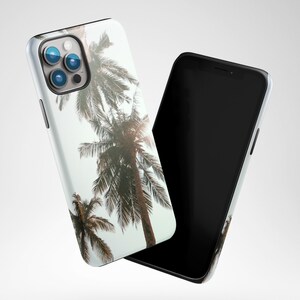 May include: A white phone case with a tropical palm tree design. The case is shown with a black phone.
