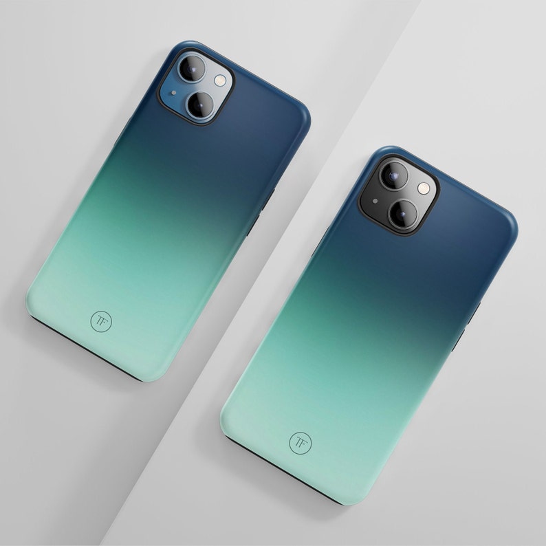 May include: Two phone cases with a gradient design, transitioning from dark blue to light blue. The cases have a circular logo with the letters "TF" in the center.