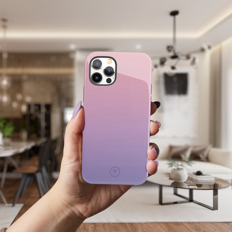 May include: A pink and purple gradient phone case with a camera lens cutout and a small circle logo. The case is made of a smooth, glossy material.