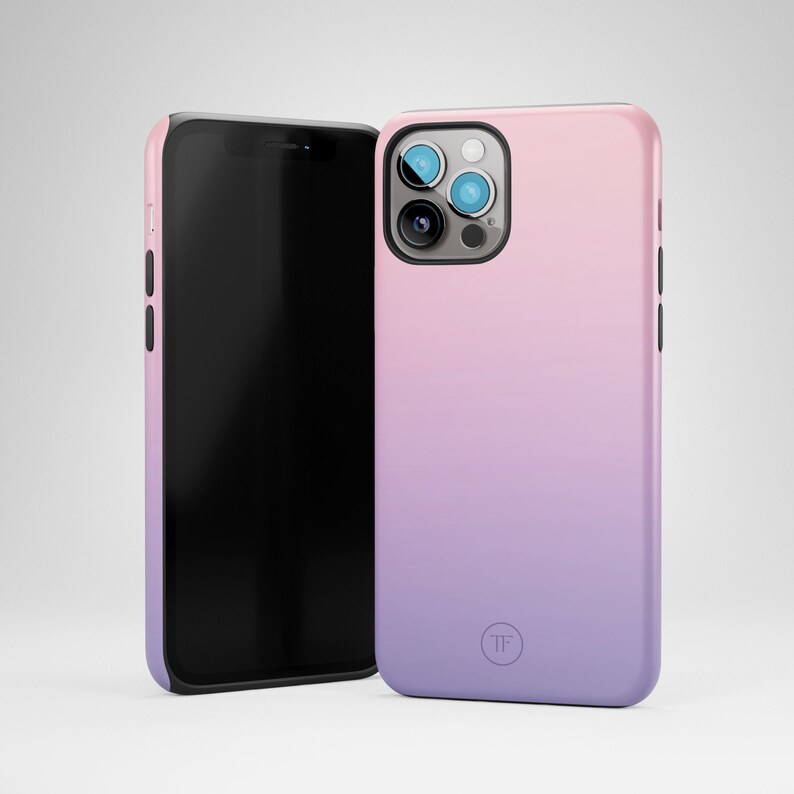 May include: A phone case with a gradient design that transitions from pink to purple. The case has a black border and a small circle with the letters "TF" in the lower right corner.