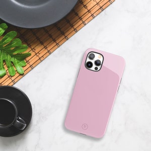 May include: A pink phone case with a clear camera lens cover and a small circle logo on the back.