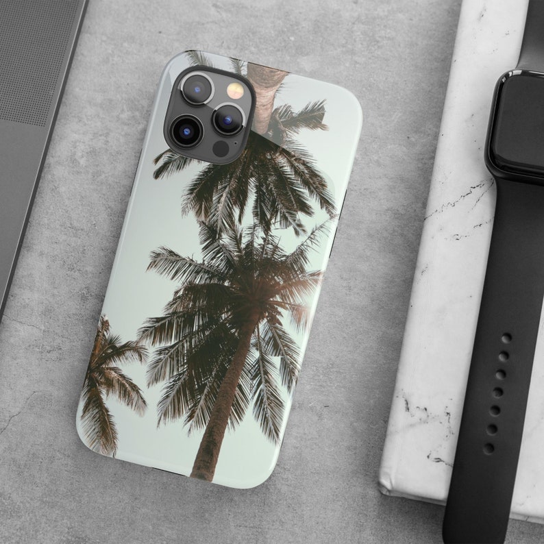 May include: A clear phone case with a tropical palm tree design. The case has a white background and features a close-up view of the palm tree leaves.