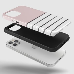 May include: A white and pink striped phone case with black stripes. The case is shown layered over a black phone case and a white phone.