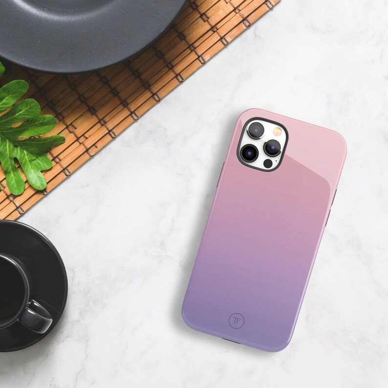 May include: A pink and purple gradient phone case with a clear camera lens cover and a small circle logo that says "TF".