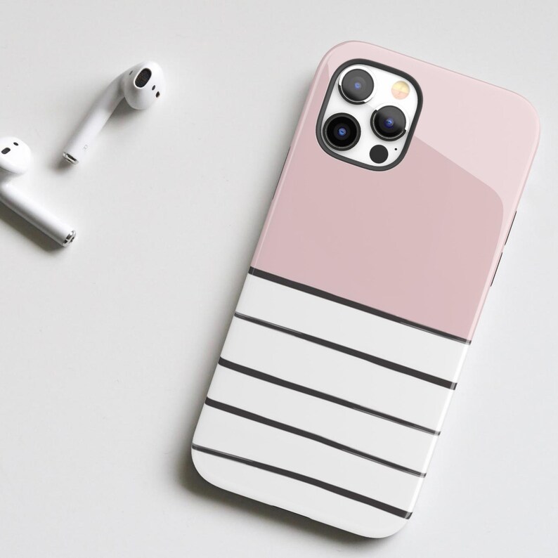 May include: A pink and white striped phone case with a black camera lens cutout. The case is made of a glossy material.