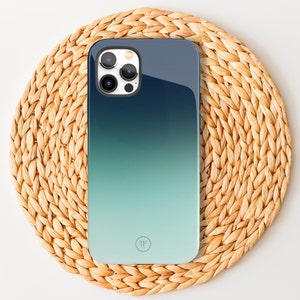 May include: A blue and green gradient phone case with a circular logo that says "TF". The case has a raised camera bump with three lenses.