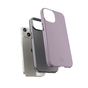 K&ouml;nnte beinhalten: Drei Handyh&uuml;llen, eine in helllila, eine in schwarz und eine in silber. Die lila H&uuml;lle hat einen kleinen Kreis mit den Buchstaben "TF" darauf. Die H&uuml;llen sind f&uuml;r ein Smartphone mit einem Dreifach-Kamerasystem.