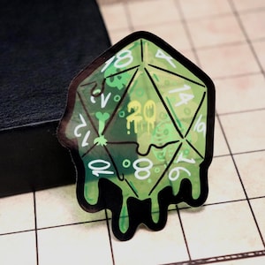 May include: A die-cut sticker shaped like a twenty-sided die, featuring a translucent lime green color with a dripping slime effect. The die has white numbers printed on its faces, with a prominent yellow number 20 in the center.