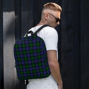Könnte beinhalten: Ein schwarzer Rucksack mit einem blau-grün-schwarzen Karomuster. Der Rucksack hat verstellbare Träger und einen Reißverschluss.