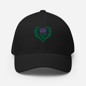 May include: Black baseball cap with an embroidered green heart containing a purple thistle.